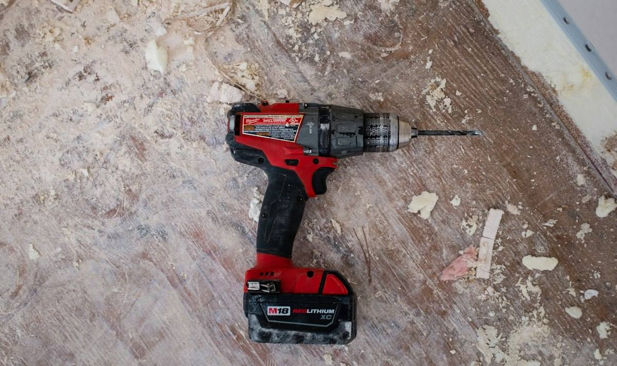 Cordless drill resting on a worn subfloor during repair work in a Tulsa OK home, the kind of surface exposed during water mitigation
